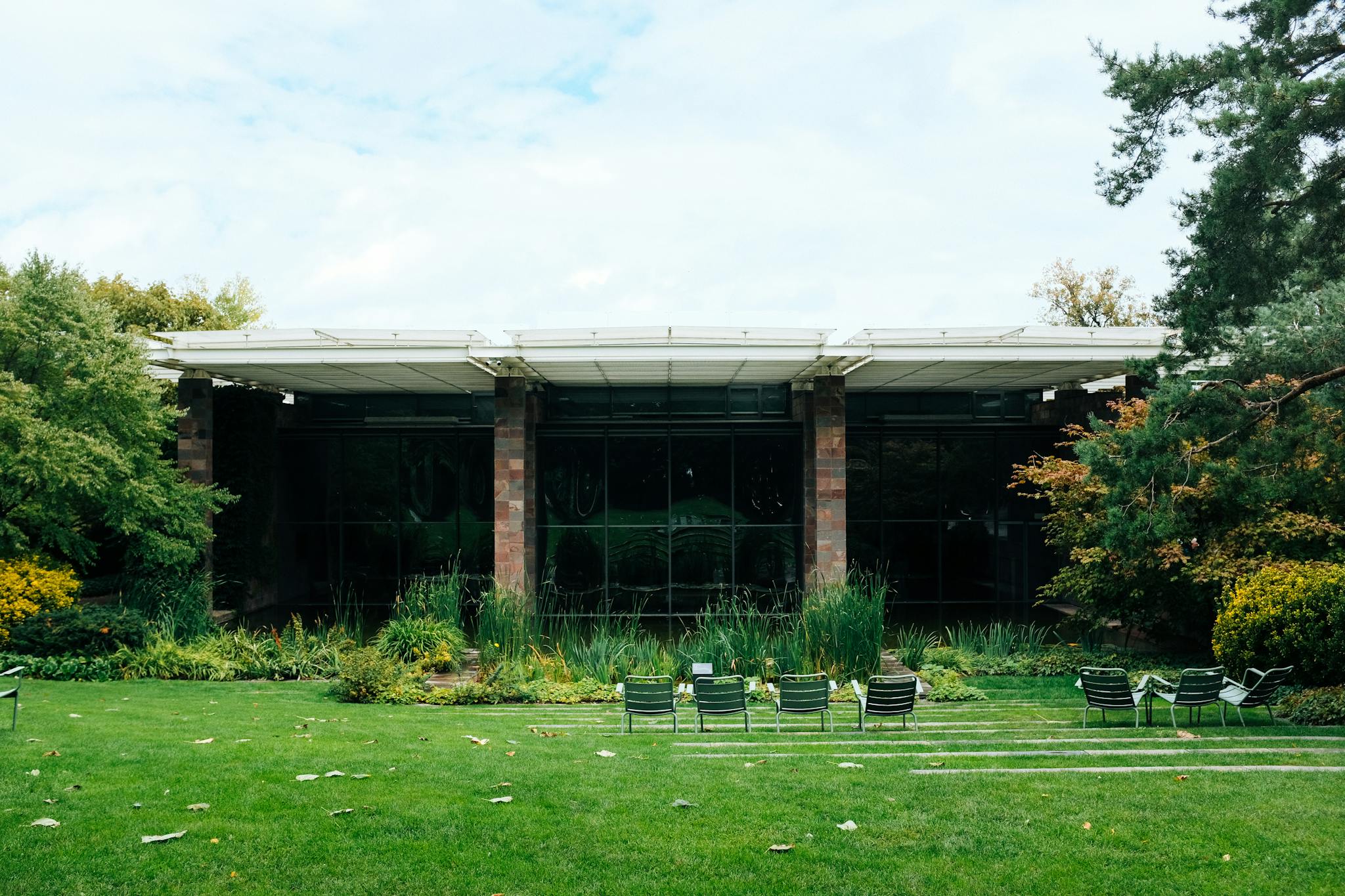 A modern house exterior with surrounding gardens and lawn chairs, ideal for outdoor relaxation.